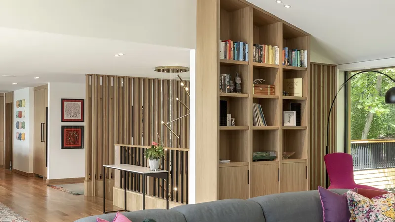 Interior with timber slatted screen dividing the living area from the built-in bookshelf wall