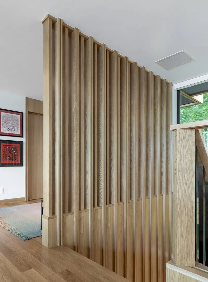 Freestanding timber slat partition extending from floor to ceiling near the entrance