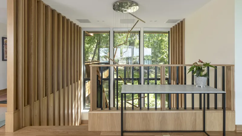 Upper landing with vertical timber screen and black metal railing overlooking the entry below