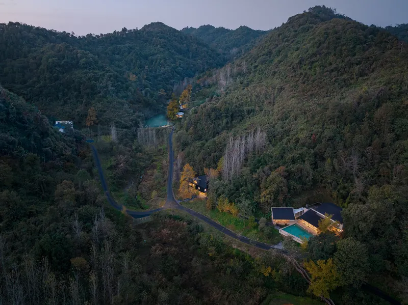 Aerial view of the residence and swimming pool nestled among forested hillsides at twilight