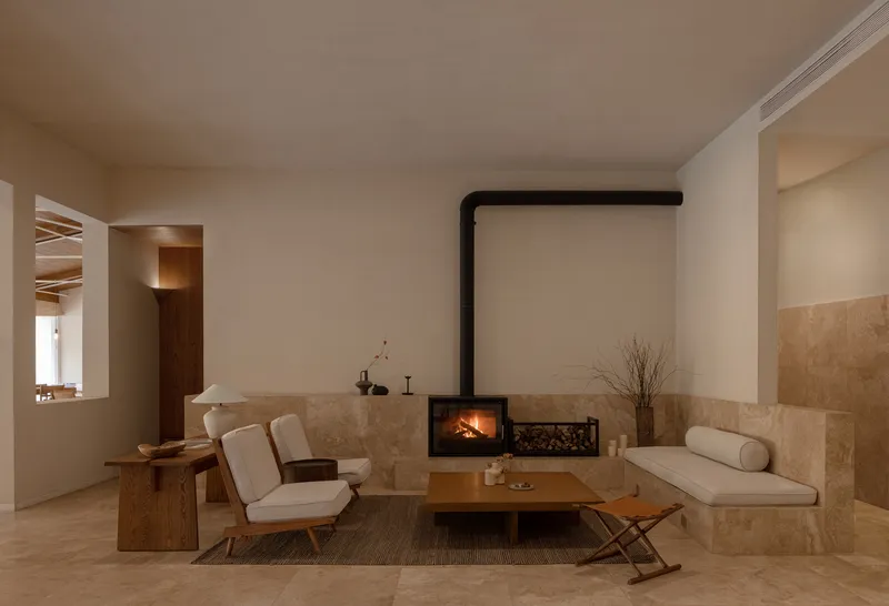Living space with suspended fireplace flanked by limestone half-walls and timber furnishings