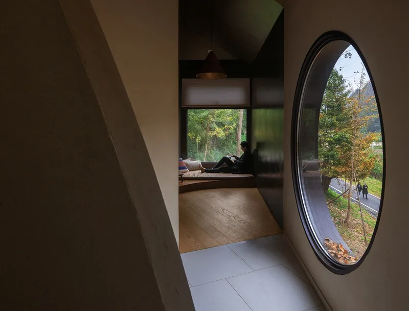 Passage with large circular window framing autumn trees and figures outside