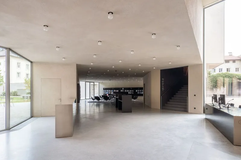 Entry foyer with polished concrete floor, pale timber ceiling with recessed lighting, and glimpse of stair beyond