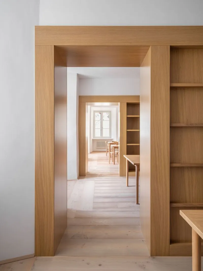 Aligned oak doorways framing a view through successive rooms to a sunlit space beyond