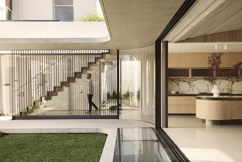 Courtyard showing the steel rod balustrade staircase rising beside a planted bed and reflecting pool