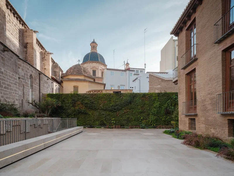 Courtyard view with planted hedge wall and tiled dome of adjacent church in the background