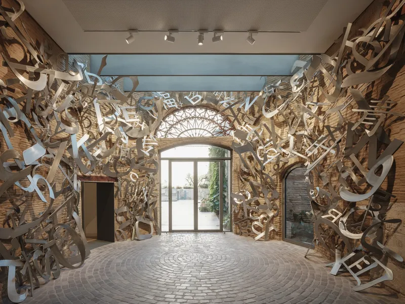 Interior entry hall with spiraling sculptural installation covering brick walls and circular paving pattern underfoot