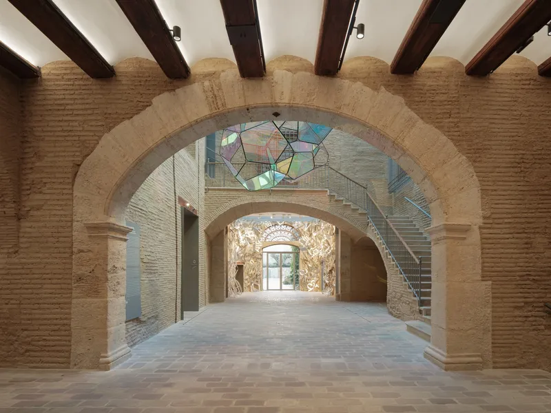 Vaulted brick archways with exposed timber beams framing views through layered gallery spaces