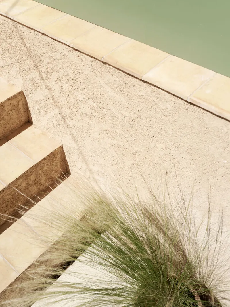 Stone stair detail with planted grass tuft beside the pale green painted wall