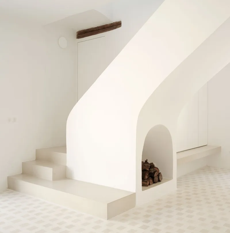 Curved white staircase with arched fireplace niche at its base