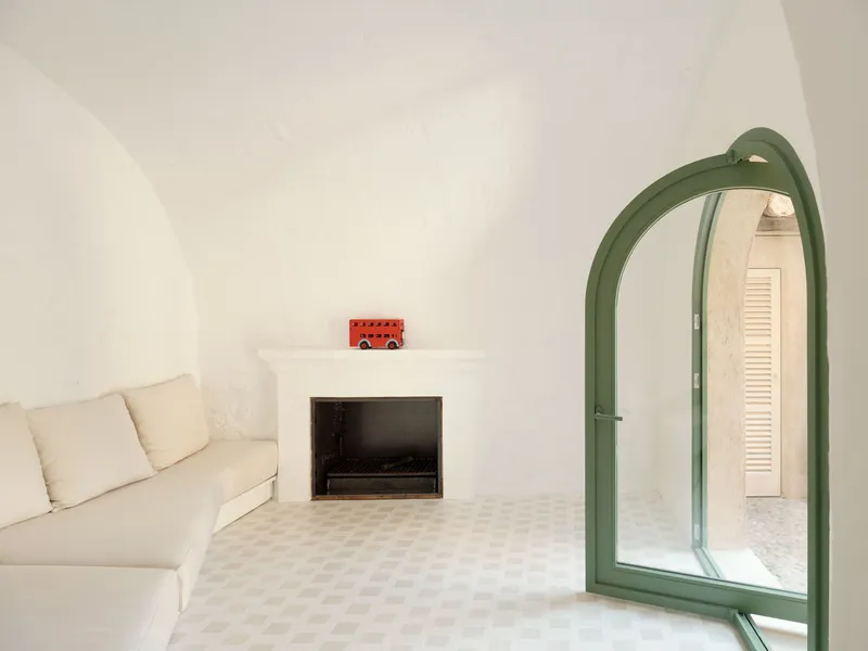 Vaulted white interior with green arched doorway and recessed fireplace niche