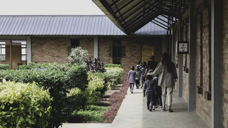 Covered walkway along planted bed and brick wall with children and adults in procession