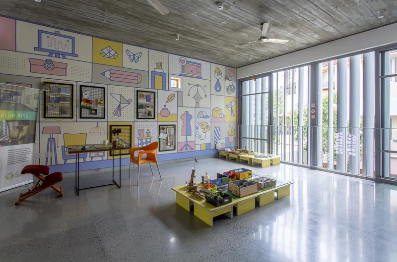Interior room with polished terrazzo floor, exposed concrete ceiling, vertical louvers at right, and illustrated mural wall at left