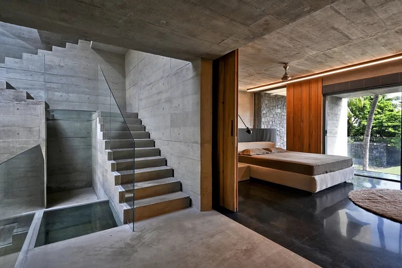 Cantilevered concrete staircase with timber treads overlooking a bedroom and reflecting pool below