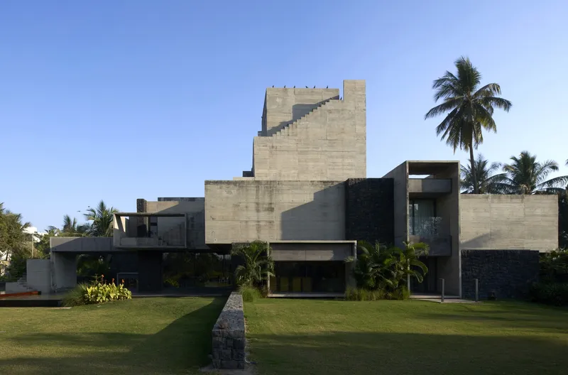 Garden elevation showing the stepped concrete tower and horizontal bands under a clear blue sky