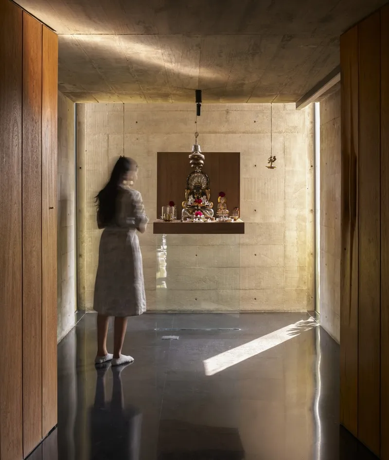 Prayer niche with board-formed concrete walls and a floating timber shelf illuminated by natural light