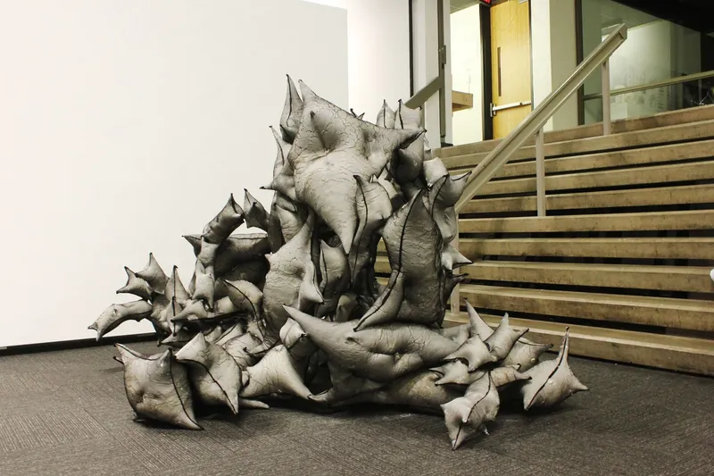 Pale sculptural form with protruding spikes installed at the base of a timber staircase