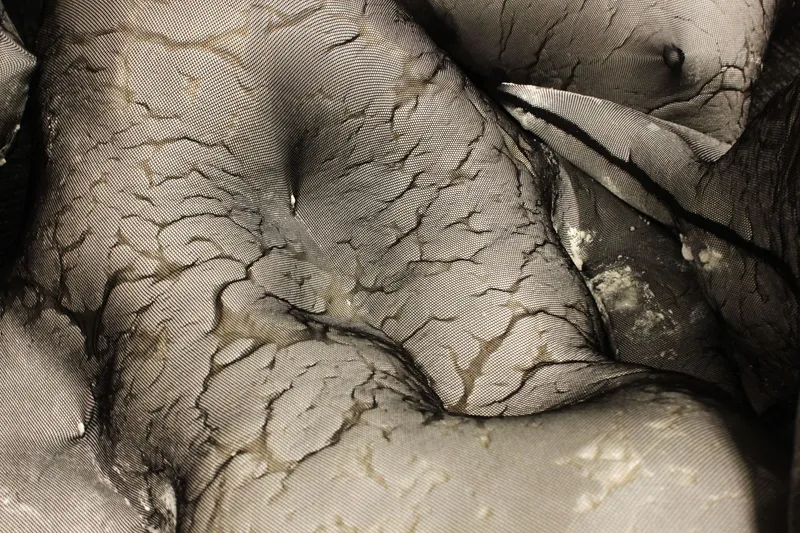 Close-up of cracked plaster surface with peeling edges revealing underlying layers