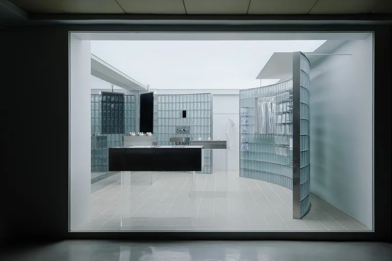 Framed view of retail interior with translucent glass block walls and a floating black display counter