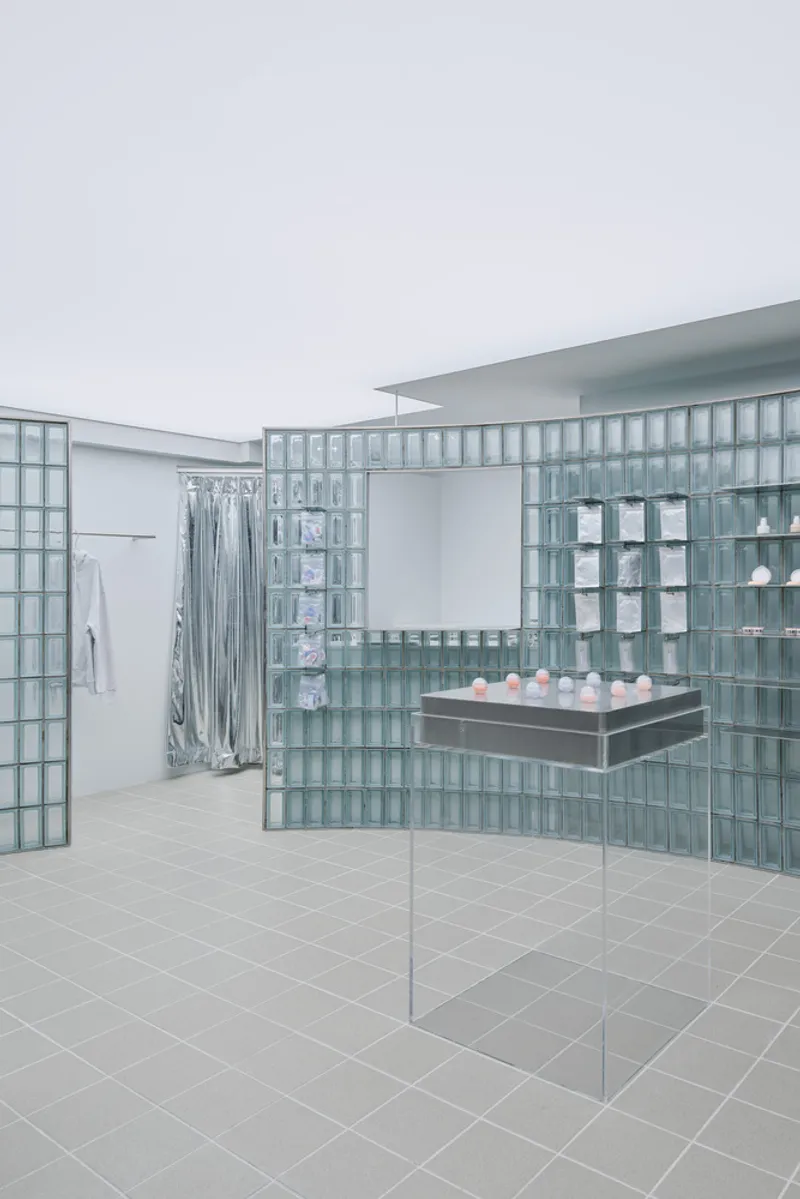 Retail space with glass block partitions and transparent shelving under diffuse overcast light