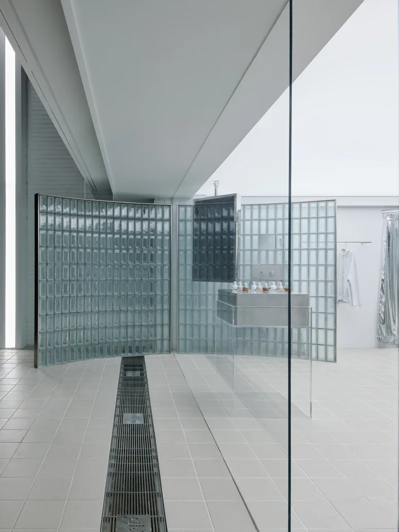 Interior corridor with linear floor drainage grate and glass block partitions dividing the retail space