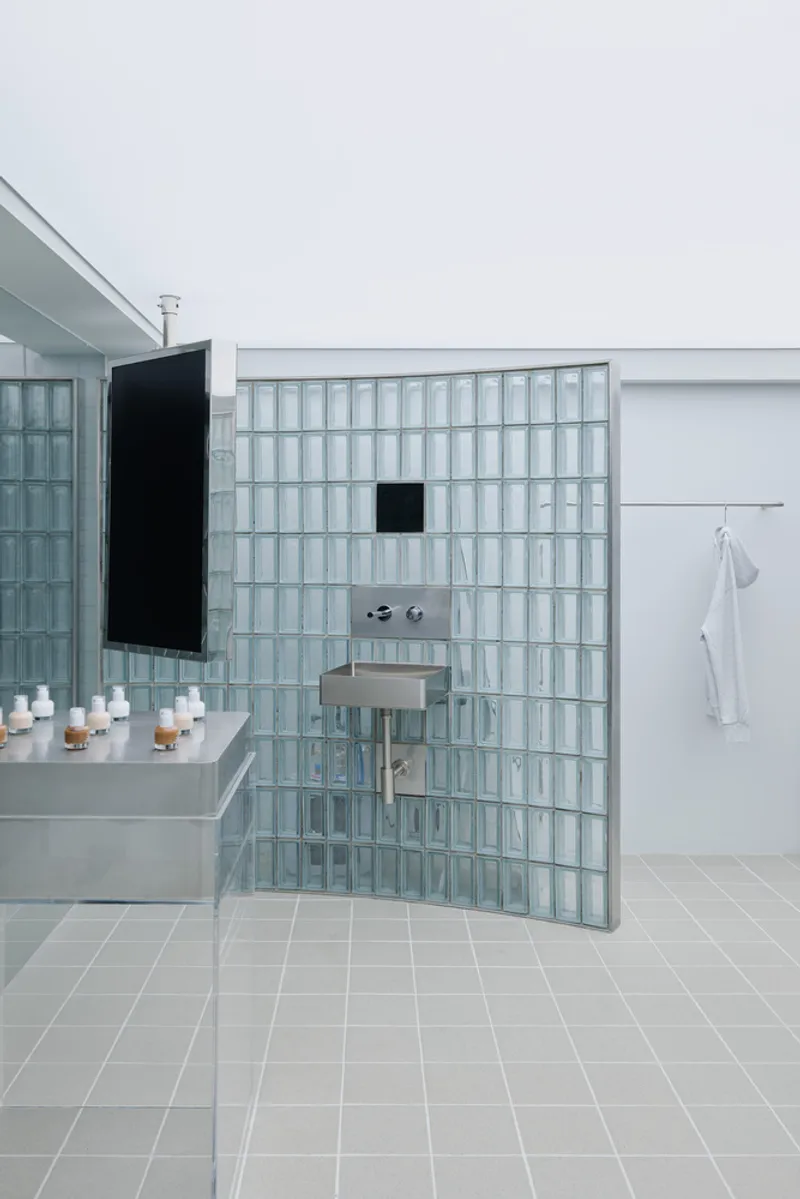 Freestanding glass block partition wall with integrated sink and mirror under soft daylight