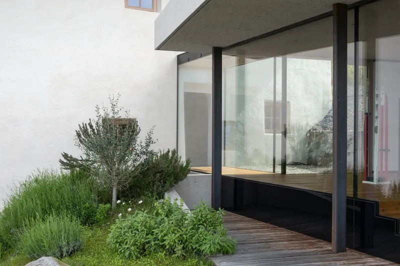 Timber deck terrace with sliding glass doors and planted bed along white stucco wall