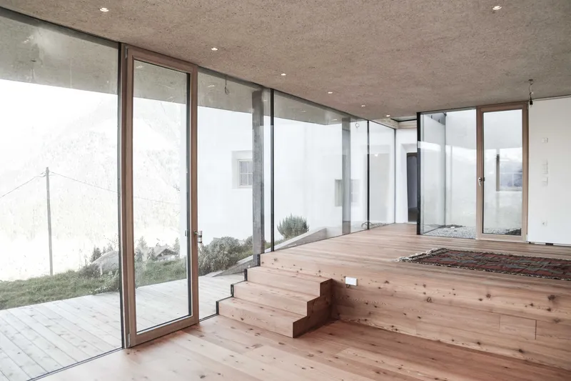 Interior stepped timber platform with full-height glazing opening to exterior courtyard garden