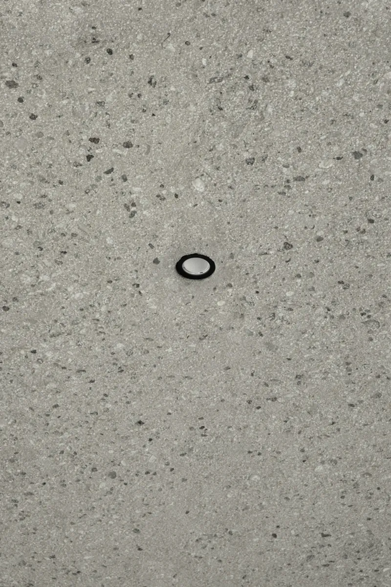 Close-up of terrazzo floor with a recessed black rubber drain grommet