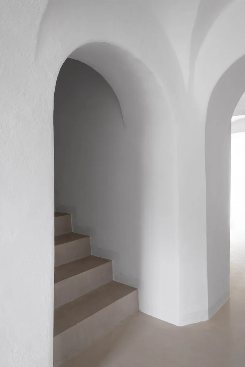 White plaster arched passage framing a staircase in soft natural light