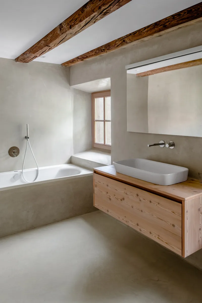 Bathroom with exposed timber beams, pine vanity and troweled plaster walls surrounding a built-in tub