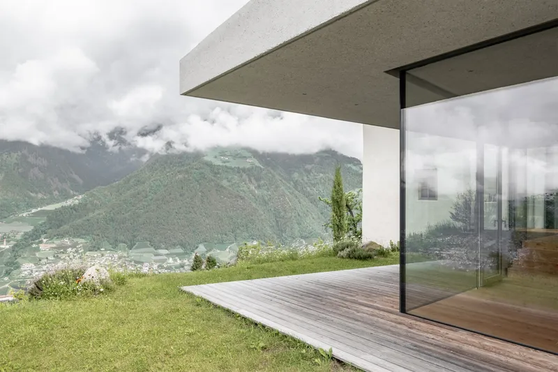 Cantilevered concrete roof framing mountain views shrouded in clouds from the timber deck