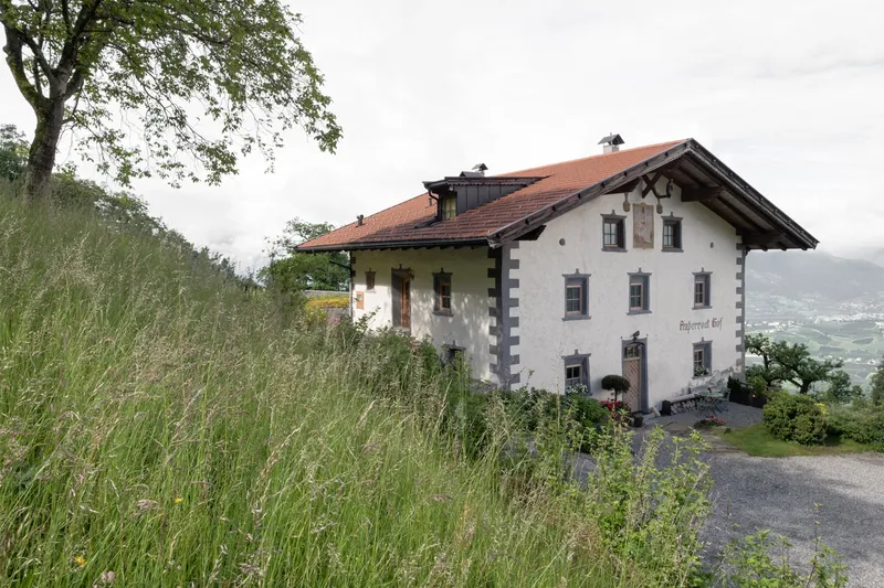 White plastered farmhouse with quoined corners and terracotta tile roof in a hillside meadow