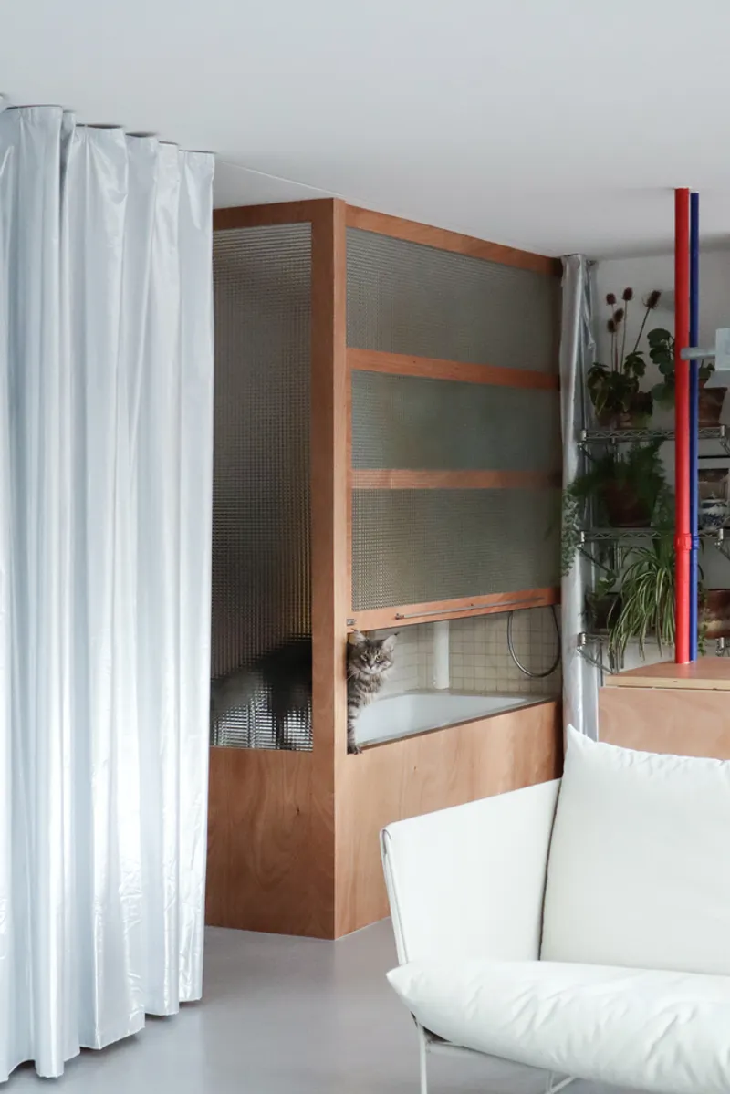 Living area with built-in timber shelving unit featuring translucent reeded glass and white curtains