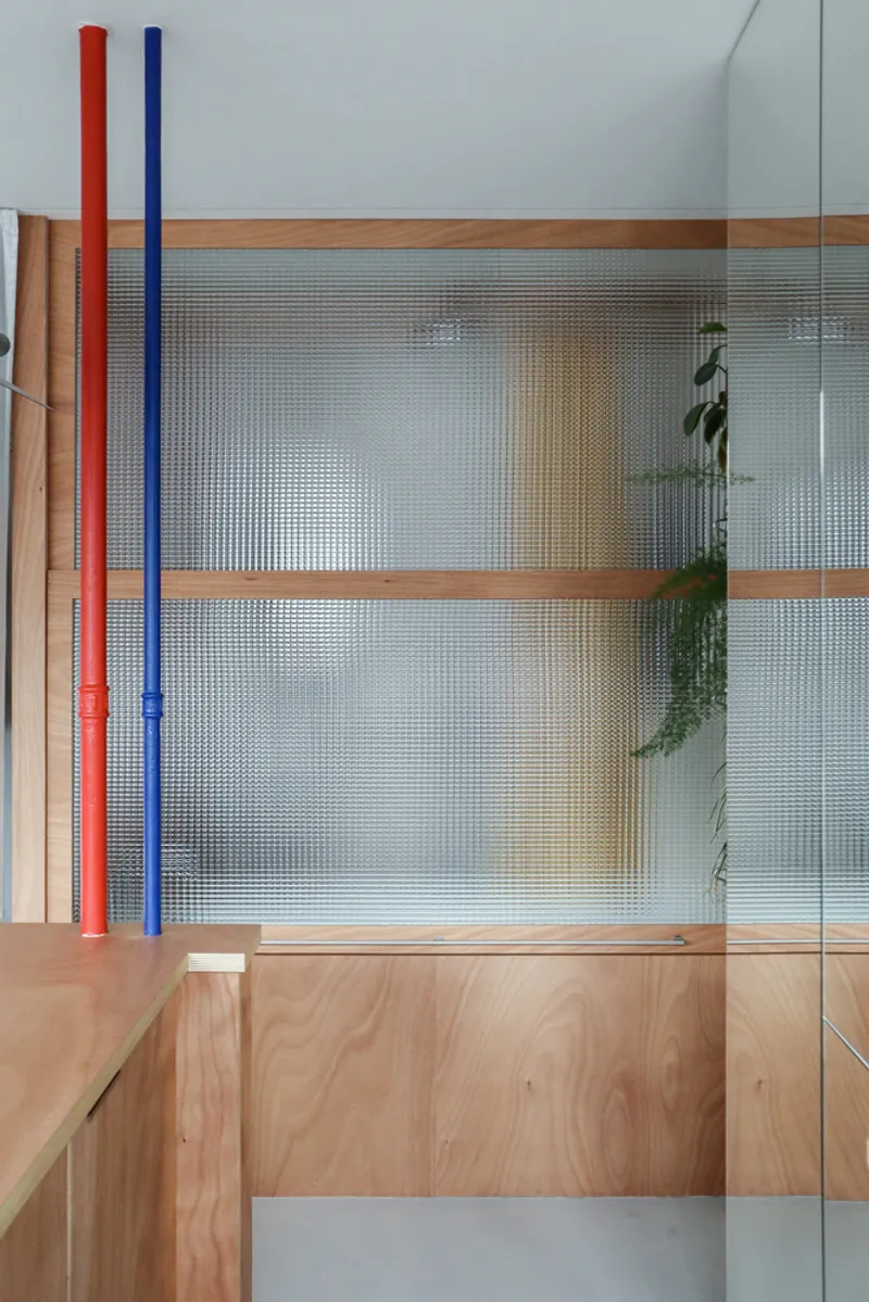 Close-up of translucent reeded glass panels set in timber frames with hanging plants visible behind