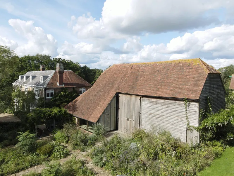 Aerial view of the tiled barn roof and glass extension surrounded by garden planting