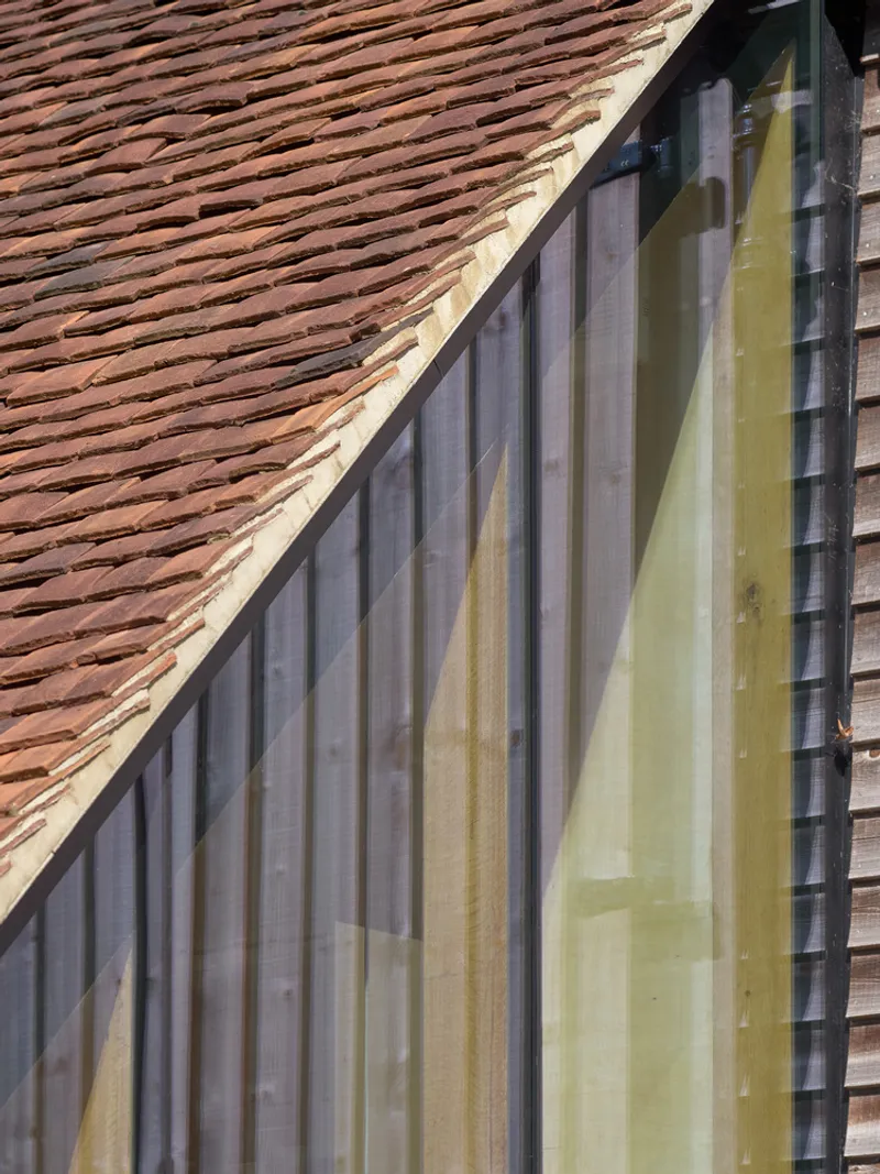 Glazed gable end with vertical timber framing beneath a clay tile roof slope