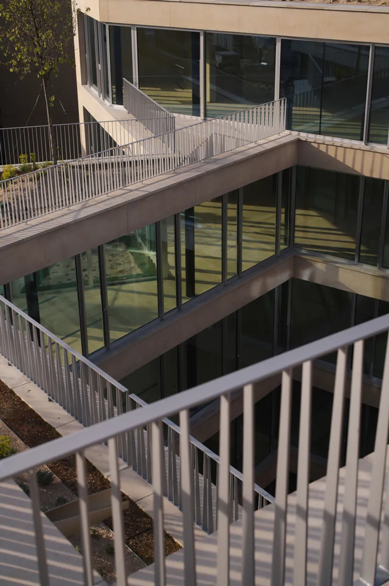 Stacked terraces with vertical metal railings, glass facades and concrete slabs viewed from an upper balcony