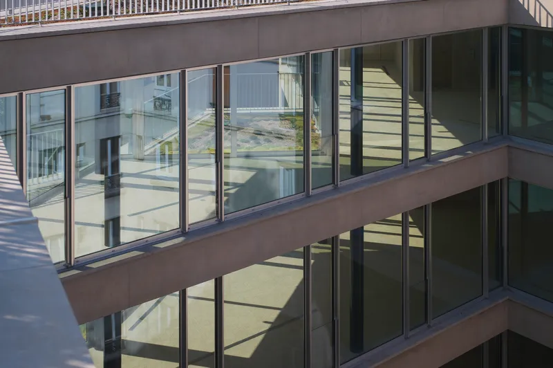 Exterior view of stacked balconies with floor-to-ceiling glazing reflecting neighboring buildings