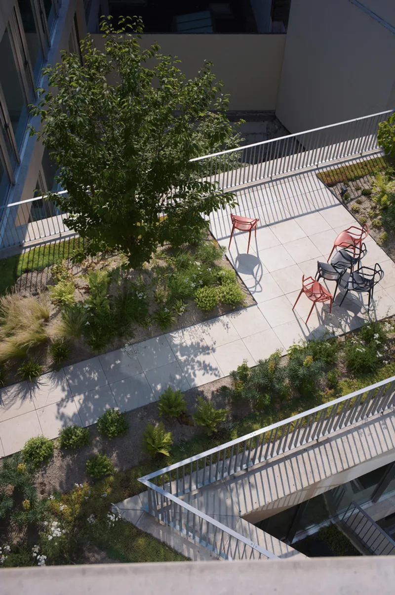 Aerial view of courtyard terrace with red chairs planted beds and corrugated metal railings
