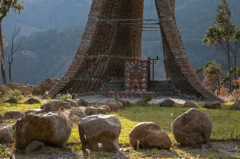 Brick tower bases with scattered boulders in a grassy clearing beneath distant mountains