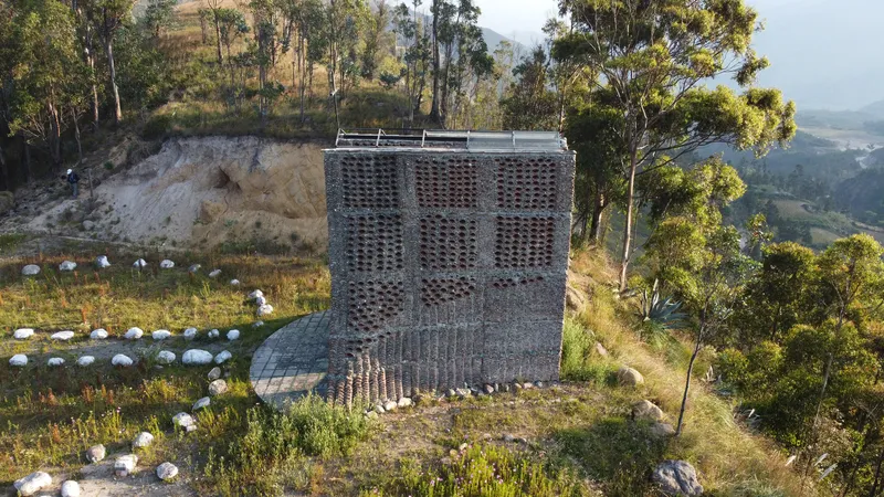 Perforated brick tower on a hillside surrounded by eucalyptus trees and stone markers