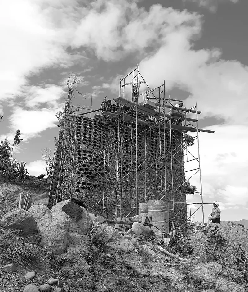 Chapel tower clad in patterned brickwork surrounded by construction scaffolding under billowing clouds