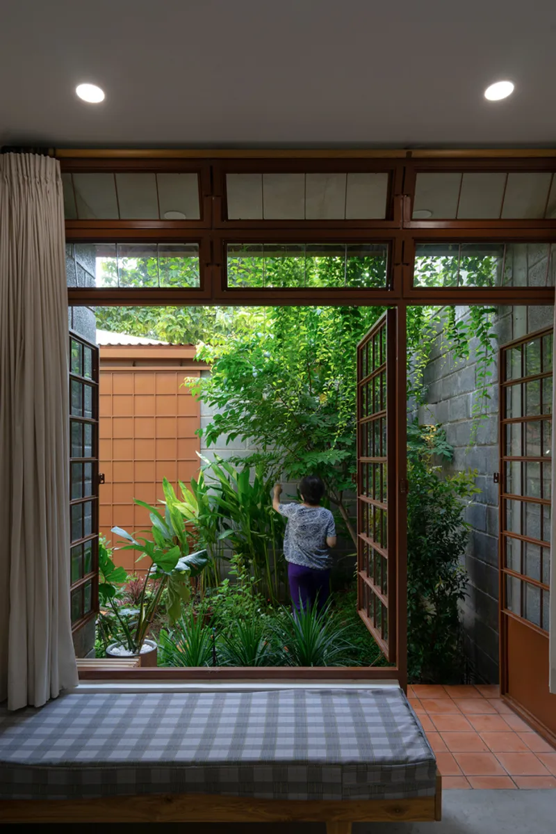 Timber framed doorway opening to a planted courtyard with a child standing among the greenery