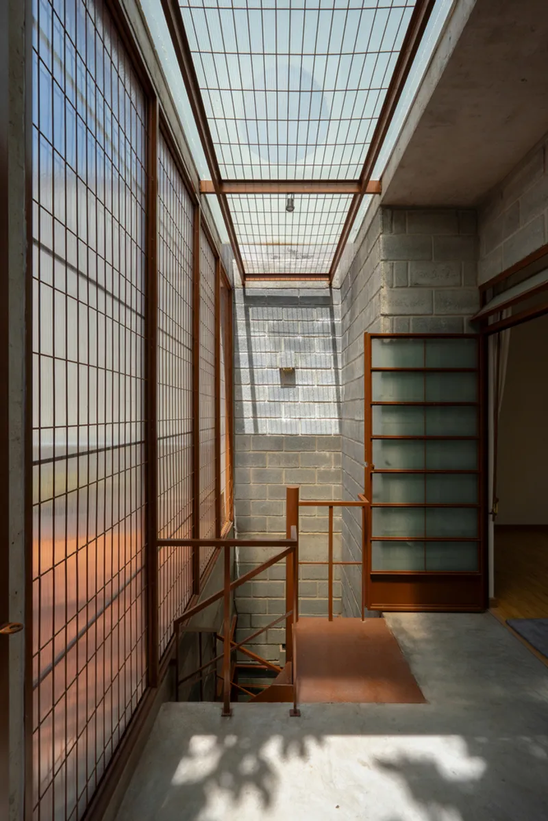 Double-height interior hallway with timber-framed glass ceiling and concrete block walls
