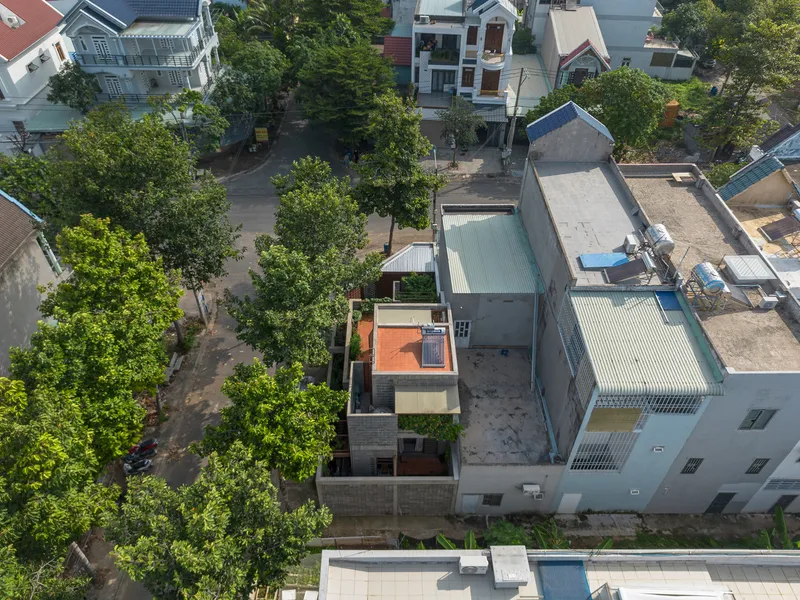 Aerial view of the narrow residence with an orange rooftop terrace nestled among dense street trees