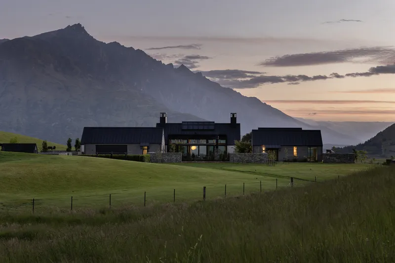 Long view of the clustered volumes in open pastureland with mountain range at sunset
