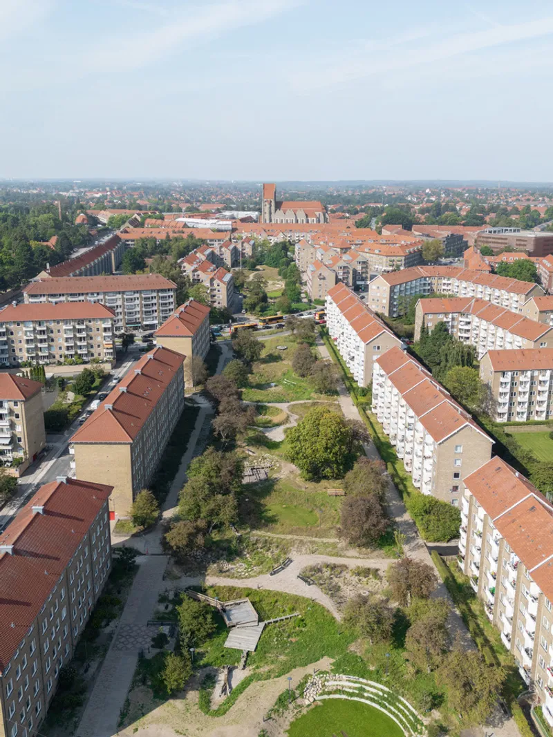 Aerial view of the linear green corridor running between residential blocks with tile roofs