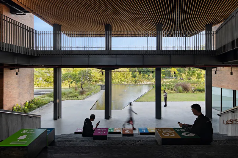 Ground floor seating area with timber batten ceiling overlooking pond and landscaped courtyard with seated visitors