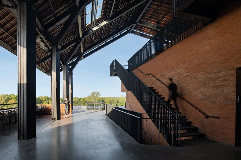 Interior view of the black steel staircase against a brick wall under an exposed timber truss roof